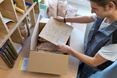 Mitarbeiter verpackt ein kleines Muster in einer Versandbox