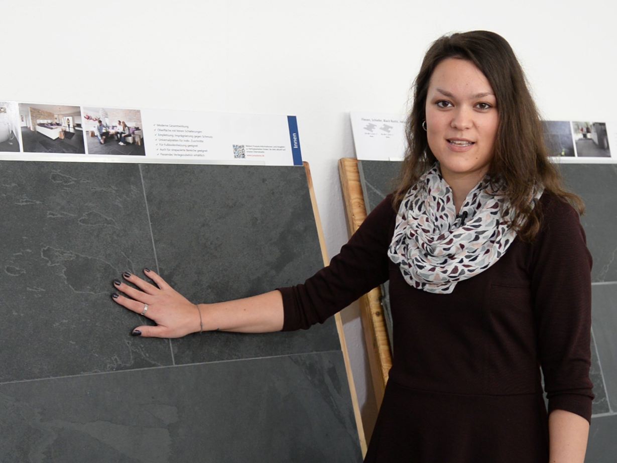 Mitarbeiterin steht vor Mustertafeln mit Schiefer