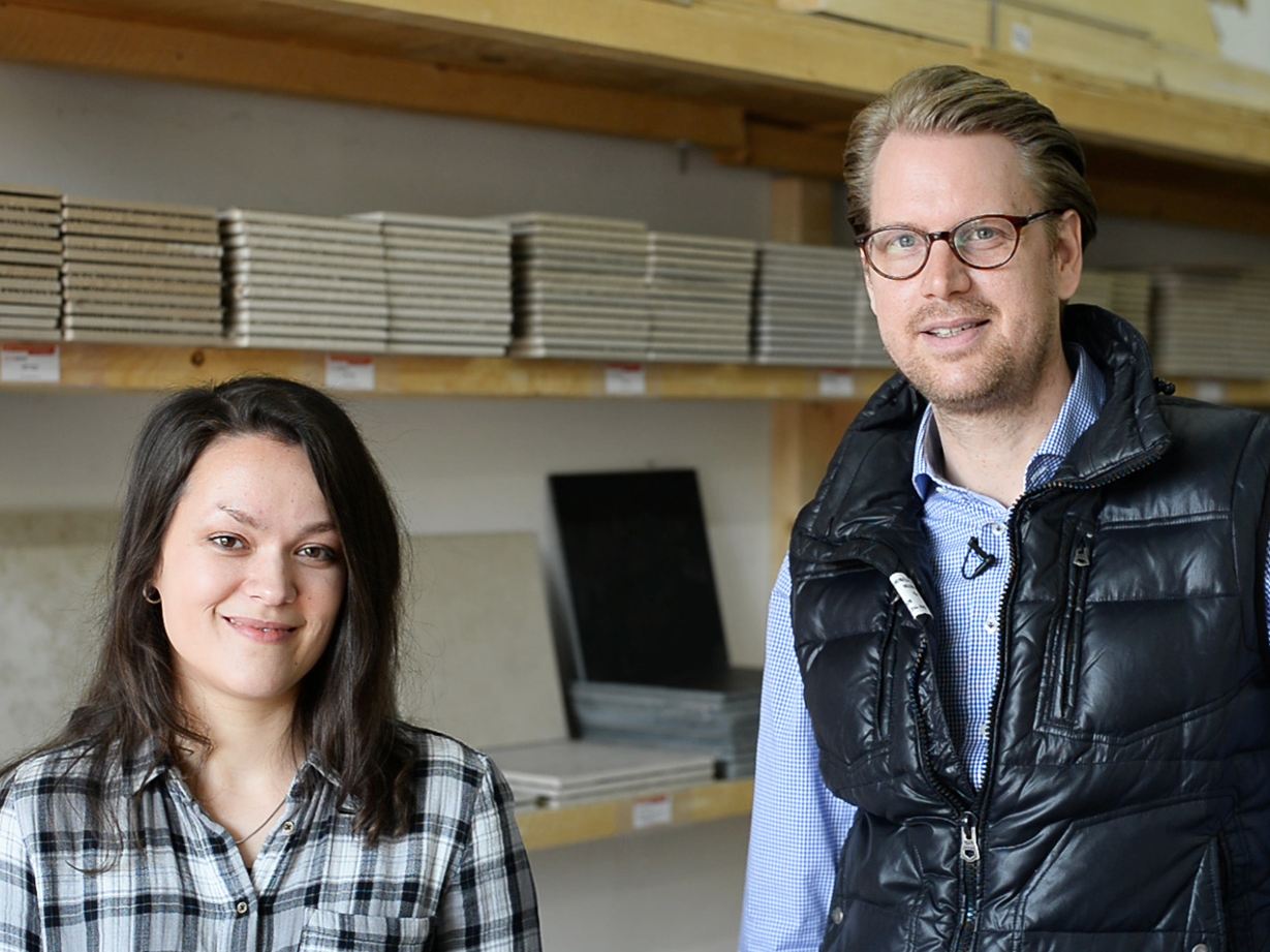 Eine Mitarbeiterin und ein Mitarbeiter vor einem Regal mit Musterfliesen