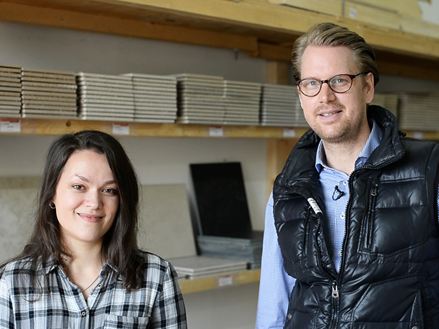 Eine Mitarbeiterin und ein Mitarbeiter vor einem Regal mit Musterfliesen