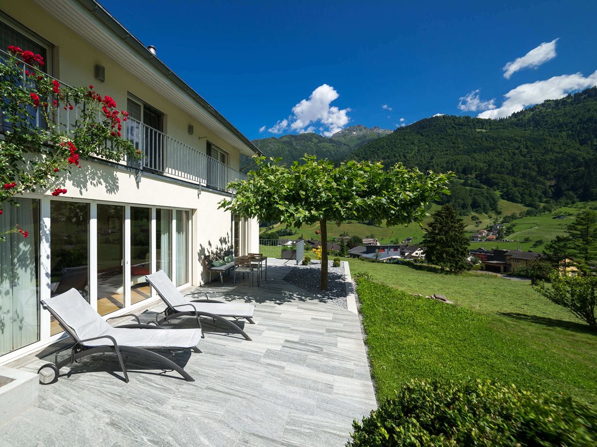 Terrasse mit Granitplatten, Liegen und Bergen im Hintergrund