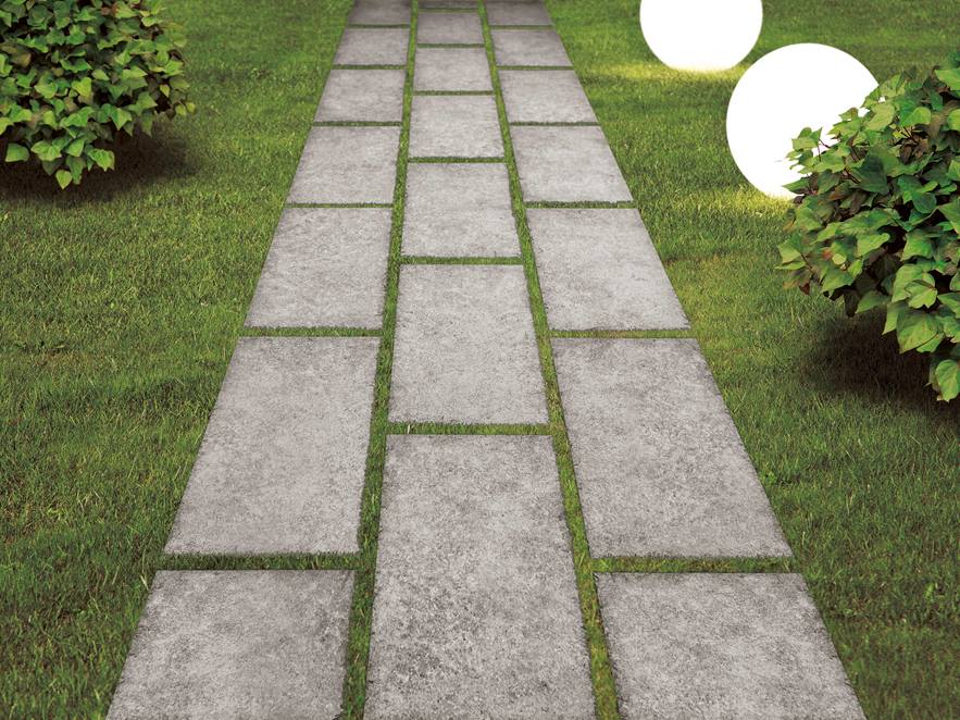 Gartenweg aus grauen Granitplatten mit Rasen und Büschen daneben