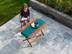 Frau sitzt an Holztisch auf einer Terrasse mit Platten aus Marmor
