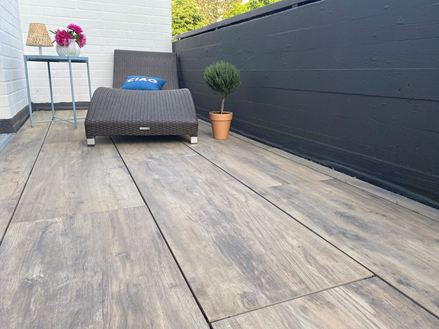Balkon mit Liege und Terrassenplatten in Holzoptik aus Feinsteinzeug als Bodenbelag