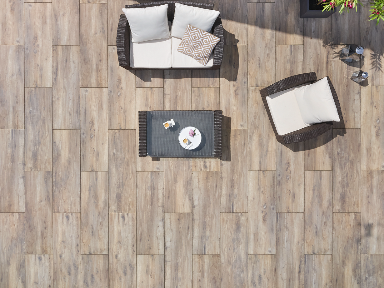 Harmonische Gesamtwirkung der verlegten Fläche Vogelperspektive auf eine Terrasse mit Platten in Holzoptik und modernen Möbeln