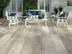 Maritime Terrasse mit Sesseln und Beistelltisch, als Bodenbelag Platten aus Feinsteinzeug in heller Holzoptik