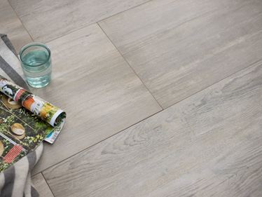 Glas und Zeitschrift auf verlegten Platten aus Feinsteinzeug in Holzoptik Nordic Maple