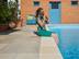 Maedchen mit Katze sitzt auf Sandsteinterrasse direkt am Pool