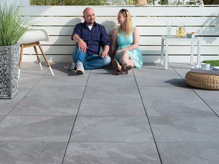 Personen sitzen auf Terrasse mit Platten in heller Schieferoptik Alpine Grey