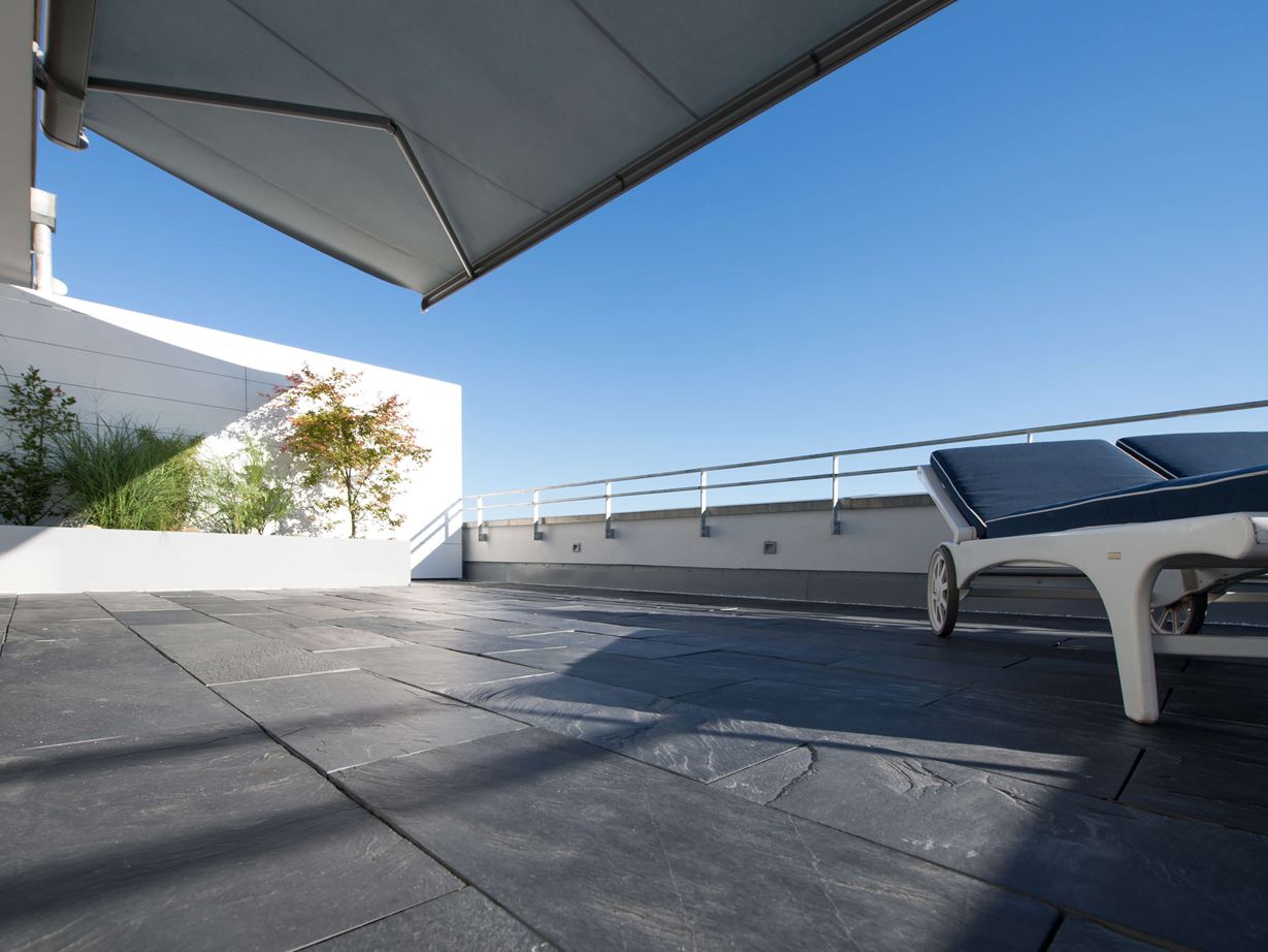 Dachterrasse mit Schiefer als Bodenbelag und Liegestühlen am Rand aus der Froschperspektive