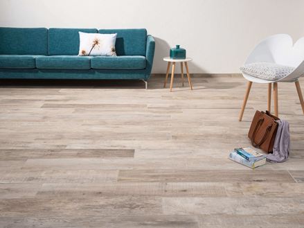 Wohnzimmer mit Fliesen in Holzoptik Indie Sky, weißem Stuhl und dunkelgrüner Couch