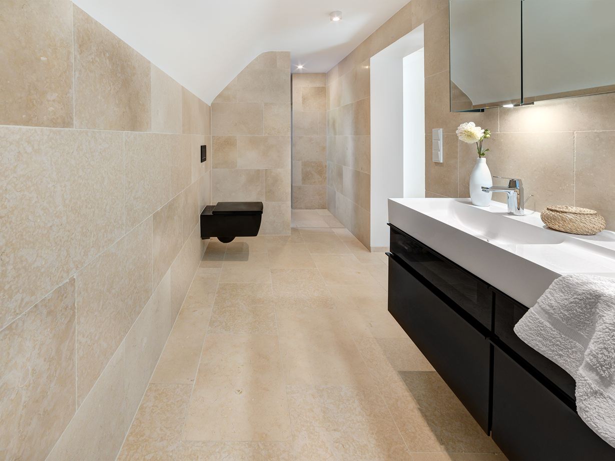 Heller Kalkstein wirkt auch auf großen Flächen harmonisch! Badezimmer mit modernen Möbeln und Kalksteinfliesen Cleopatra Light auf dem Boden und an der Wand
