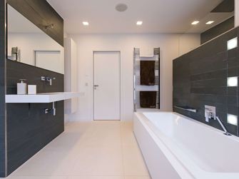 Modernes Bad mit hellen Kalksteinfliesen als Bodenbelag und dunklem Schiefer an der Wand