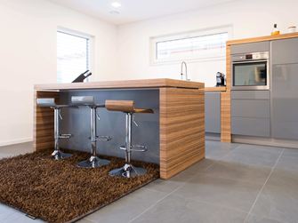 Küche mit freier Bartheke, modernen Holzelementen und dunklem Schiefer als Bodenbelag