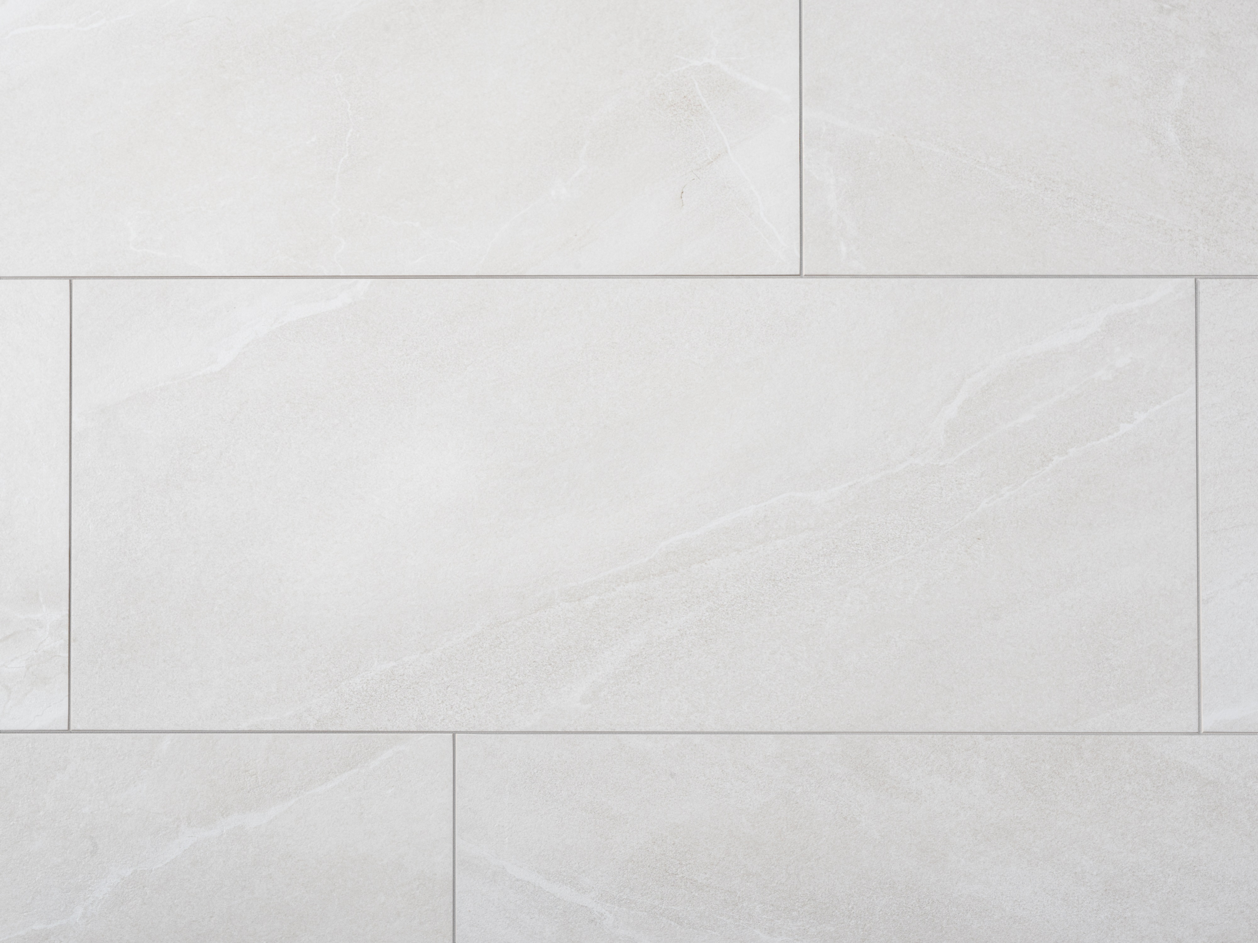 Nahaufnahme von hellgrauen Schieferoptik-Fliesen aus Feinsteinzeug mit schmalen Fugen