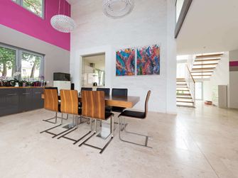 Offener Essbereich mit modernen Holzstühlen und buntem Gemälde an der Wand, Bodenbelag helle Travertinfliesen mit geschliffener Oberfläche