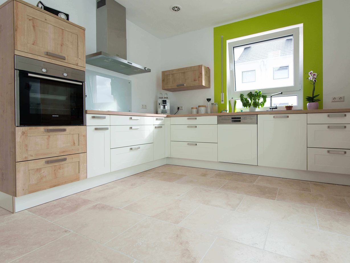 Küche in Weiss mit Holzelementen und grüner Fensterumrahmung auf Travertinfliese Light mit getrommelter, ungespachtelter Oberfläche Küche in Weiss mit Holzelementen und grüner Fensterumrahmung auf Travertinfliese Light mit getrommelter, ungespachtelter Oberfläche