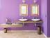 Badezimmer mit lila Wand und zwei Spiegeln auf Travertinfliese Light mit getrommelter Oberfläche