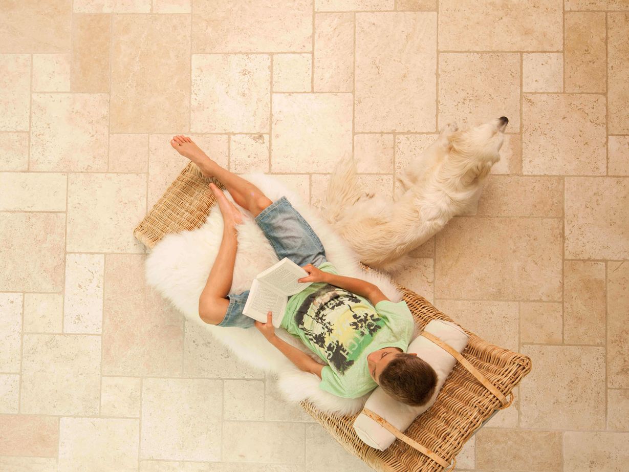 Lebendiges Wohngefühl im mediterranen Stil Junge liest im Liegestuhl auf Travertinfliesen Light im Römischen Verband verlegt