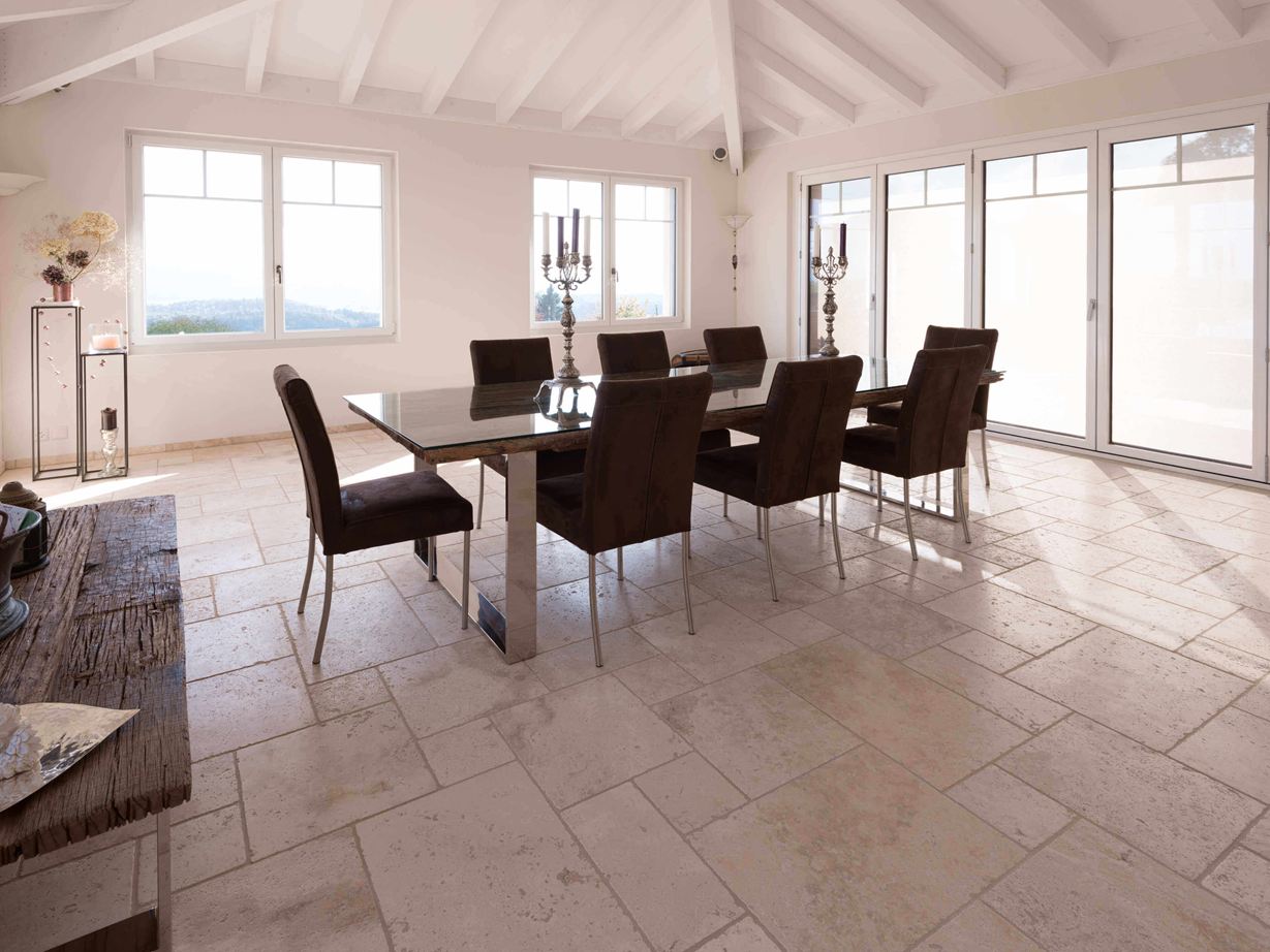 Esszimmer mit hoher Decke, Tisch und Stühlen auf Travertin Light in römischem Verband