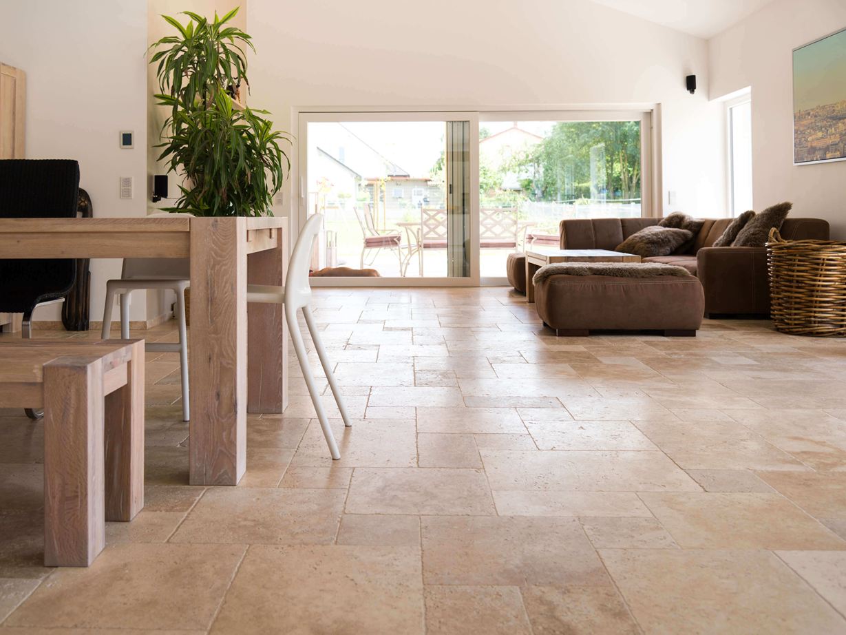 Wohnzimmer mit brauner Couch, weißen Wänden und Travertinfliesen Medium in Braun-Beige als Bodenbelag