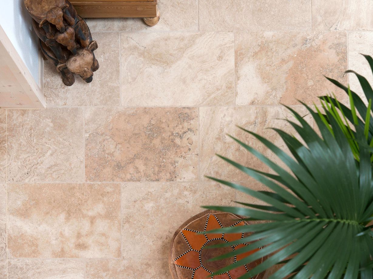 Travertin Fliese Rustic: mit typischer, charmanter Porenstruktur Aufnahme von verlegtem Travertin Fliese Rustic mit Pflanzen und Holzaccessoires aus der Vogelperspektive