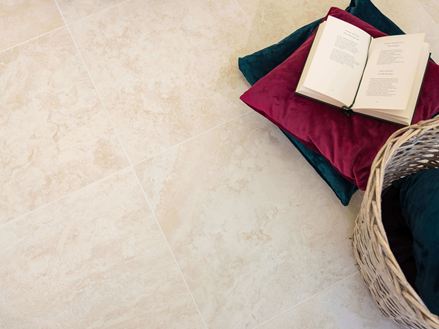 Fliesen aus Travertinoptik mit Kissen und einem aufgeschlagenen Buch
