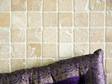 Nahaufnahme Travertin Mosaik in sanftem Beige mit lila Kissen