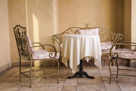 Elegante Sitzmöbel im französischen Stil mit hellem Natursteinboden
