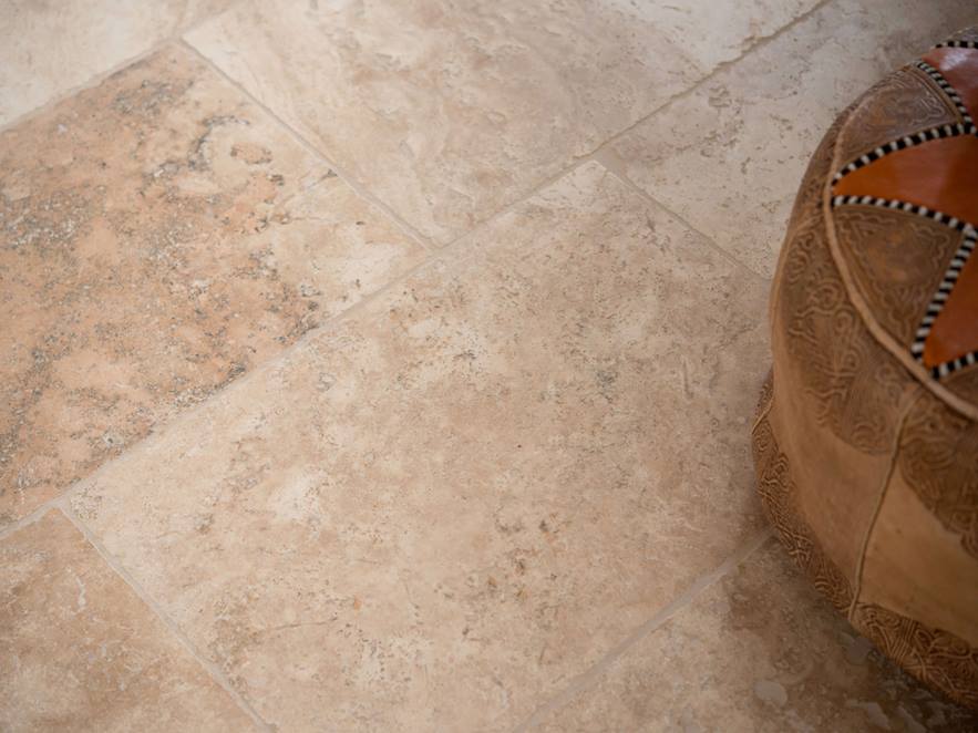 Verlegte Travertinfliese Rustic in Braun und Beige mit Dekokissen