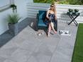 Frau sitzt auf Terrasse, Platten Alpine Grey