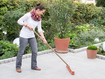 Frau reinigt Granit Mundo Grau-Terrasse