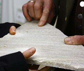 Zwei Hände halten ein Stück Naturstein aus Taunus Quarzit