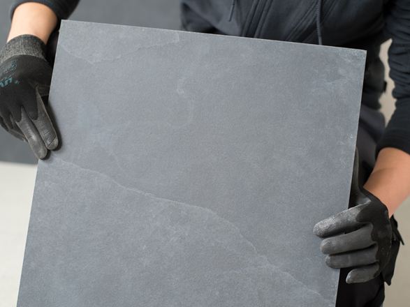 Fliesenleger hält eine Schieferfliese in die Kamera