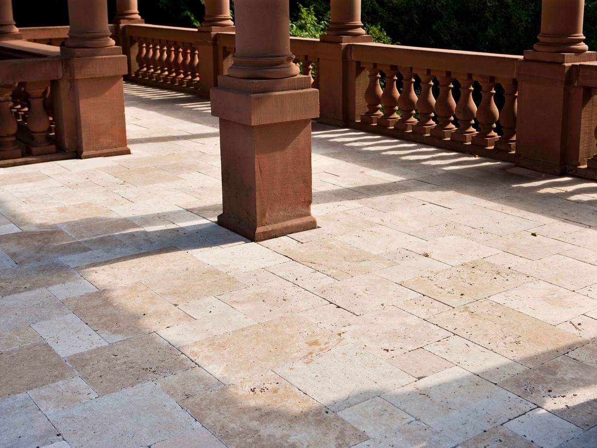 Ein Format mit Tradition: der römische Verband Schlossterrasse mit Säulen aus Naturstein und Natursteinplatten aus Travertin als Bodenbelag